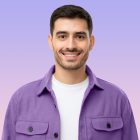 Close-up portrait of young handsome smiling man wearing purple shirt and white t-shirt, isolated on purple background